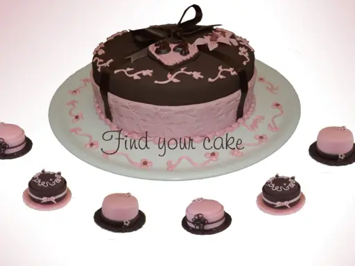 Torta centrale marrone e rosa con decorazioni in pasta di zucchero, circondata da mini-torte.