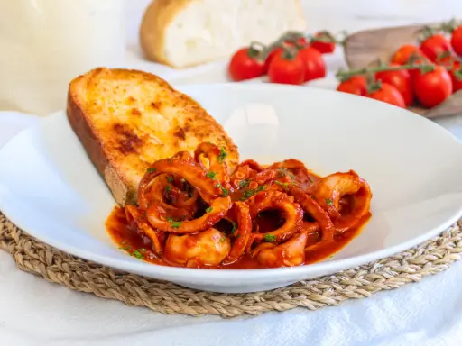 Moscardini in umido succulenti, serviti con pane tostato e pomodorini freschi. Un piatto che sa di mare e tradizione.