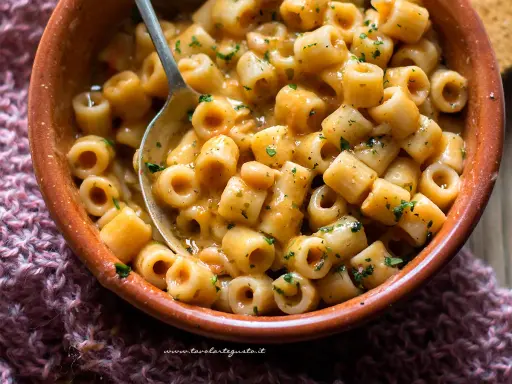 Un piatto fumante di pasta e fagioli, con ditalini e fagioli bianchi in un sugo cremoso, guarnito con prezzemolo tritato.
