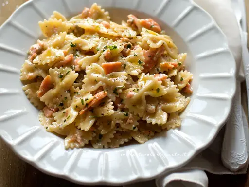 Farfalle cremose con salmone affumicato, un piatto gustoso e invitante, guarnito con prezzemolo fresco e pepe nero.