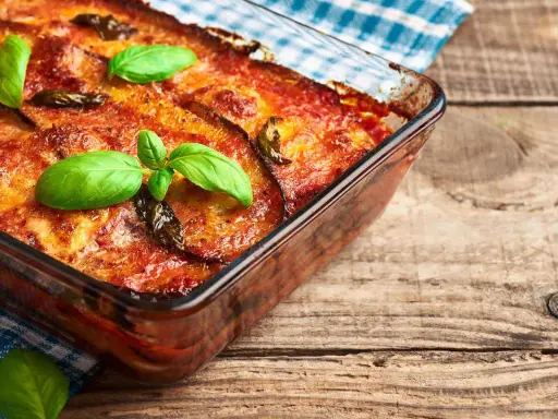 Parmigiana di melanzane in friggitrice ad aria, dorata e profumata, guarnita con basilico fresco. Un piatto gustoso e leggero.