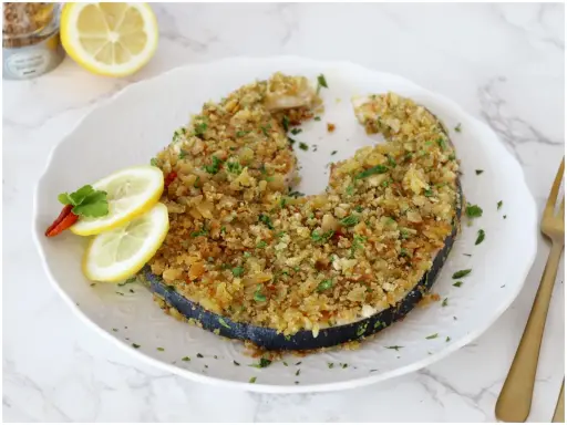 Un invitante pesce spada alla palermitana, dorato e croccante, guarnito con limone e peperoncino.