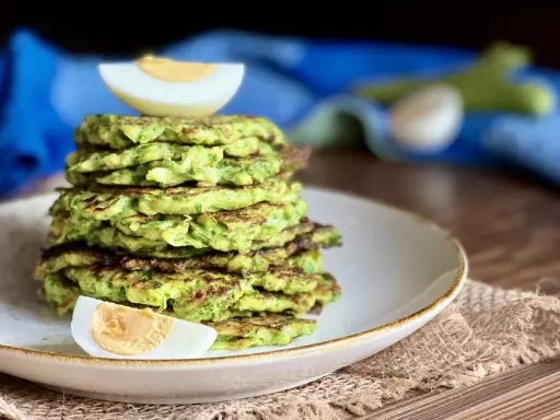 Pila di rosti di zucchine dorati, guarnita con spicchi di uovo sodo. Un piatto leggero e gustoso, perfetto per ogni pasto.