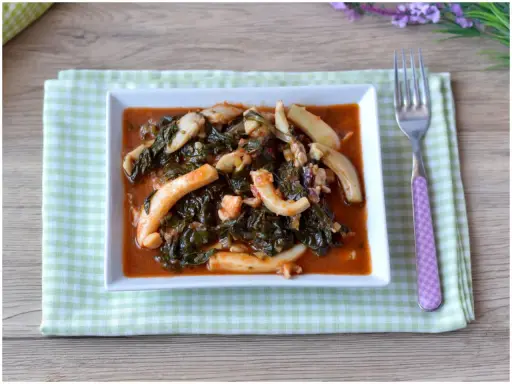 Un saporito piatto di seppie in zimino, con verdure scure e salsa rossa, servito su un tovagliolo a quadretti verdi.
