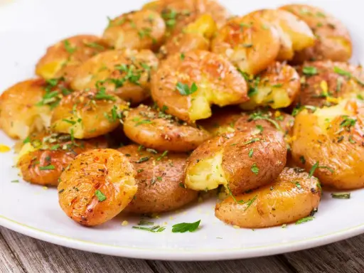 Patate lesse in friggitrice ad aria, croccanti e dorate, condite con erbe aromatiche fresche.