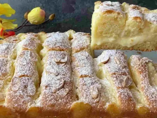 Torta al limone velocissima, soffice e profumata, cosparsa di zucchero a velo e mandorle. Una fetta mostra il ripieno cremoso.