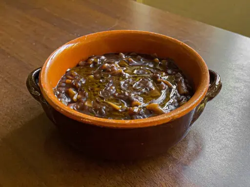 Una ciotola di terracotta con un saporito piatto di pasta e lenticchie, condito con olio d'oliva.