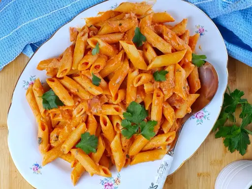 Penne al baffo cremose e saporite, guarnite con prezzemolo fresco, servite su un piatto elegante.