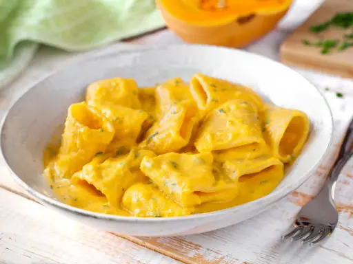 Piatto di pasta e zucca cremoso, con un tocco di erbe aromatiche. Un comfort food autunnale da gustare.