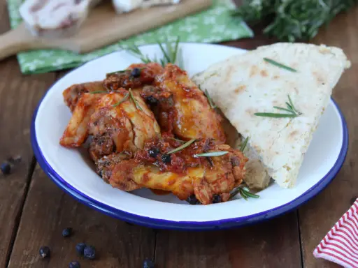 Piatto di friccò di pollo succulento con rosmarino e pane rustico su un piatto smaltato.