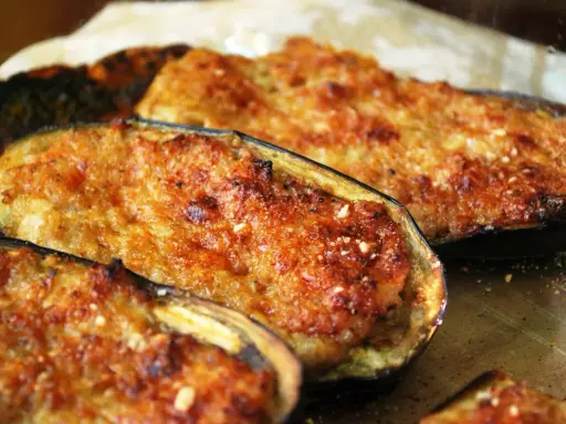 Melanzane ripiene di carne, dorate e gratinate, pronte per essere gustate. Un piatto saporito e invitante.