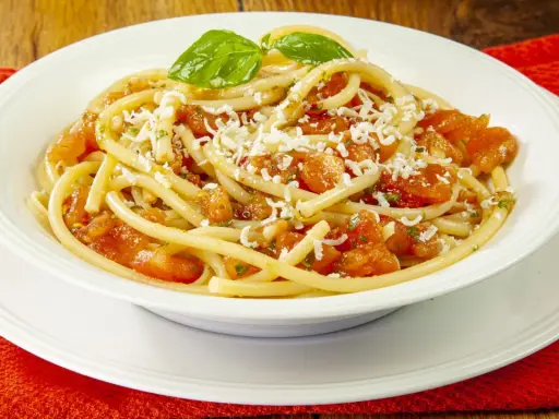 Un piatto di pasta alla carrettiera fumante, con pomodoro fresco, basilico e abbondante formaggio grattugiato.