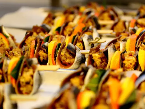 Sarde a beccafico su spiedini, con fette d'arancia e limone, un antipasto siciliano colorato e invitante.