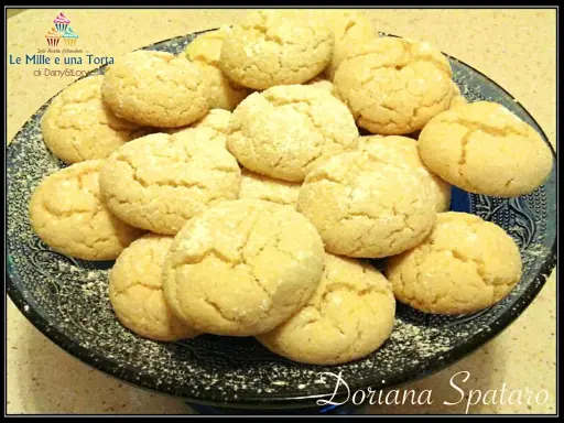 Un piatto di biscotti con farina di mandorle, spolverati di zucchero a velo, invitano a un momento di dolcezza.