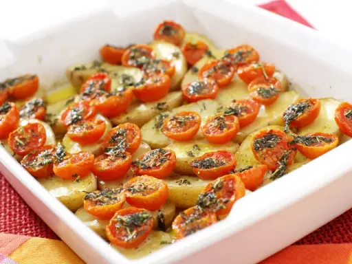 Parmigiana di patate al forno con pomodorini e erbe aromatiche, un piatto semplice e gustoso.