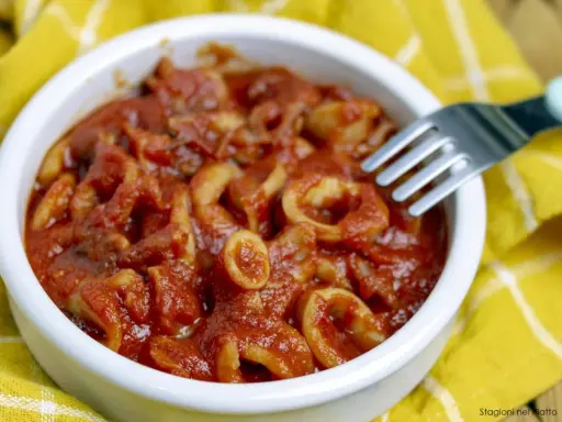 Calamari in umido, un piatto saporito e profumato, servito in una ciotola bianca su un tovagliolo giallo.