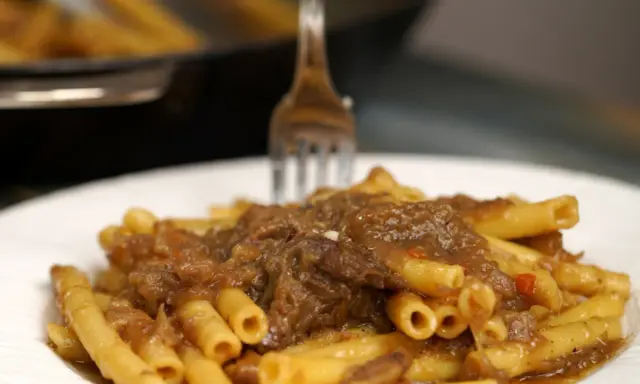 Un piatto invitante di ziti alla genovese, con la pasta condita da un ricco ragù di carne e cipolle.