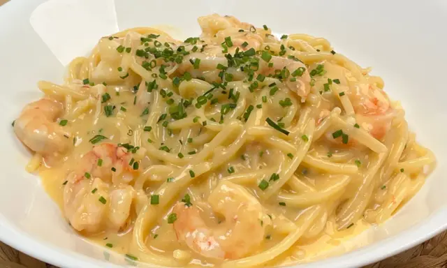 Spaghetti cremosi con gamberi e erba cipollina, una deliziosa carbonara di pesce.