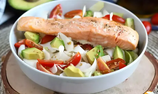 Salmone cotto su un letto di avocado, pomodorini e cipolla bianca, un piatto leggero e gustoso, perfetto come secondi di pesce.
