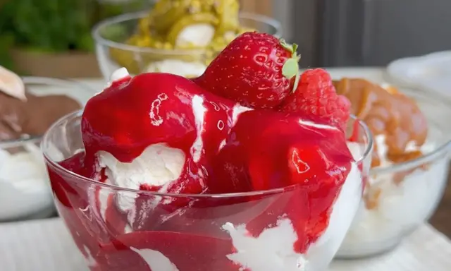 Coppetta di gelato alla fragola, con fragole fresche e salsa rossa. Scopri come fare il gelato senza gelatiera per un dessert delizioso.
