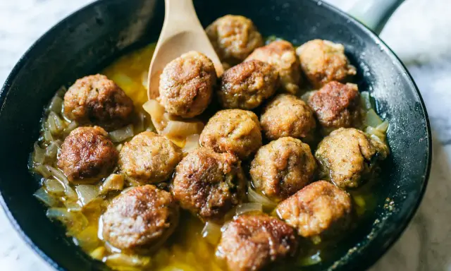 Polpette di carne morbide in padella, dorate e succulente, cuociono in un sughetto saporito con cipolle.