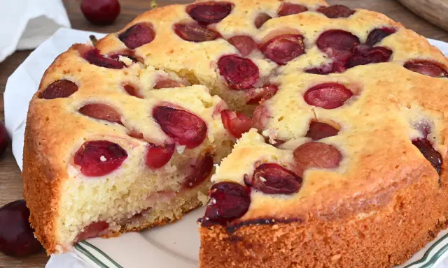Una deliziosa torta alle ciliegie, con la crosta dorata e tante ciliegie rosse immerse nell'impasto soffice.