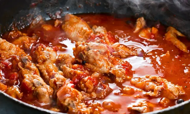 Carne alla pizzaiola morbida che sobbolle in padella, con pomodoro e profumi invitanti.