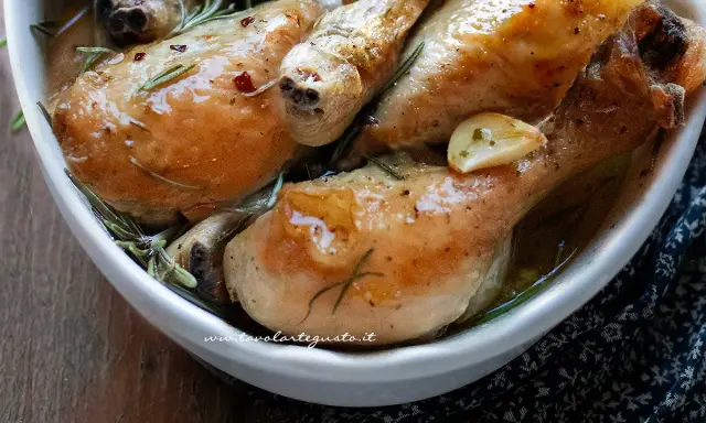 Cosce di pollo succulente, dorate e profumate al rosmarino e aglio, servite in una ciotola bianca.