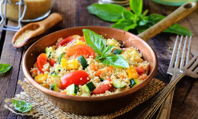 Un piatto colorato con cous cous, pomodori, zucchine e peperoni, perfetto per una ricetta cous cous originale e fresca.
