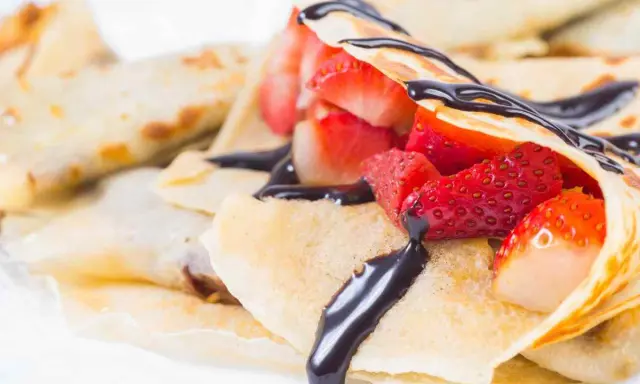 Deliziose crepes senza burro, ripiene di fragole fresche e ricoperte da una cascata di cioccolato fondente.