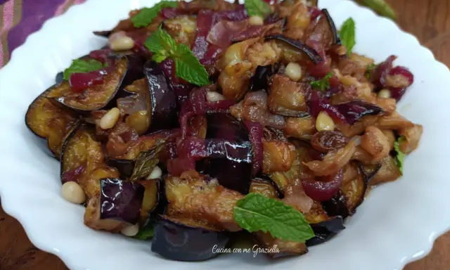 Melanzane in agrodolce, un piatto saporito con cipolle rosse, pinoli e menta fresca. Un'esplosione di gusto!