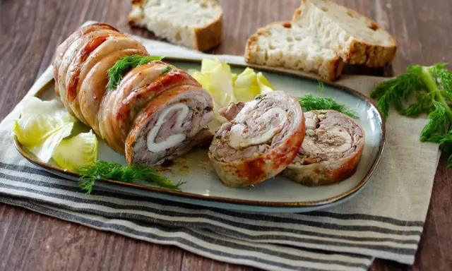 Coniglio in porchetta, un rotolo di carne succulento con erbe aromatiche, servito con pane tostato e insalata.