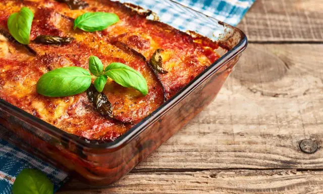 Parmigiana di melanzane in friggitrice ad aria, dorata e profumata, guarnita con basilico fresco. Un piatto gustoso e leggero.