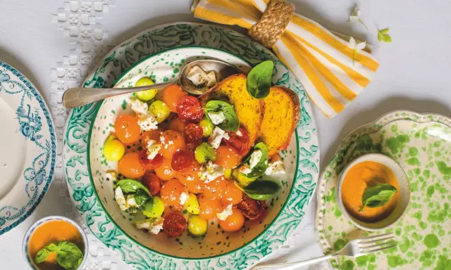 Deliziosa insalata con melone, pomodorini, formaggio e basilico, servita con pane tostato e una ciotolina di gazpacho.