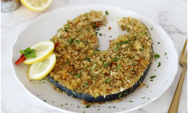 Un invitante pesce spada alla palermitana, dorato e croccante, guarnito con limone e peperoncino.