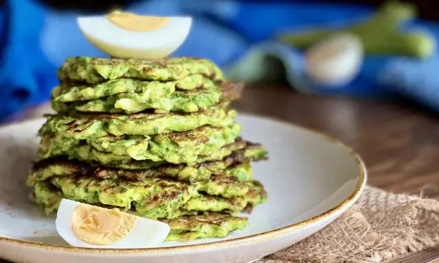 Pila di rosti di zucchine dorati, guarnita con spicchi di uovo sodo. Un piatto leggero e gustoso, perfetto per ogni pasto.