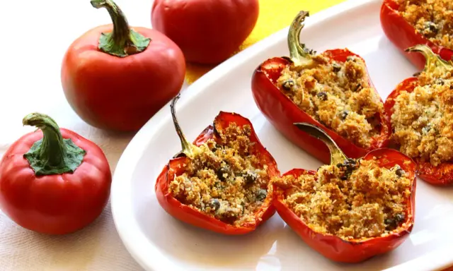 Peperoni ripieni di tonno e pangrattato, dorati e invitanti, su un piatto bianco.