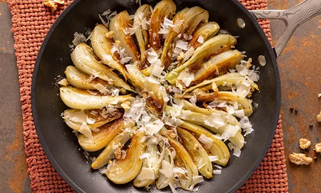 Finocchi in padella dorati, guarniti con scaglie di formaggio e noci croccanti. Un contorno saporito e invitante.