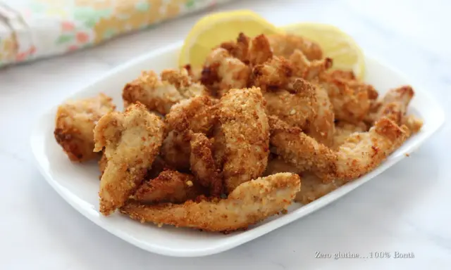Straccetti di pollo in friggitrice ad aria, dorati e croccanti, serviti con spicchi di limone.