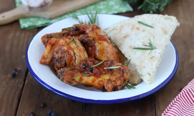 Piatto di friccò di pollo succulento con rosmarino e pane rustico su un piatto smaltato.