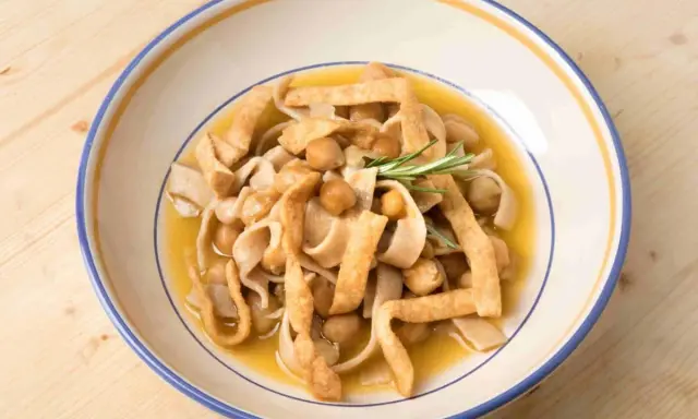 Piatto di ciceri e tria, pasta fresca con ceci e croccanti straccetti fritti, guarnito con rosmarino.