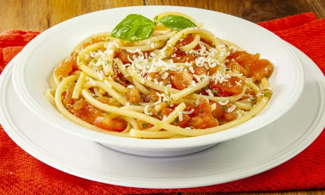 Un piatto di pasta alla carrettiera fumante, con pomodoro fresco, basilico e abbondante formaggio grattugiato.