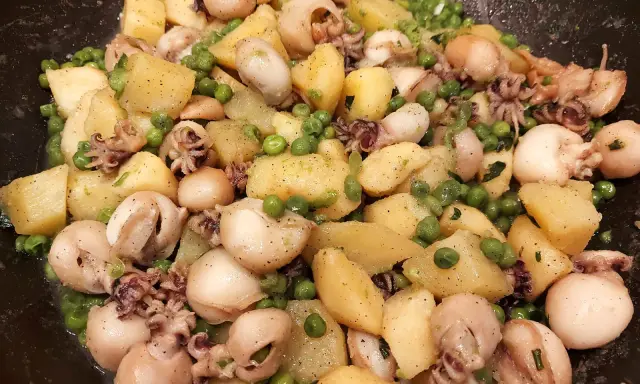 Un gustoso piatto di seppie e patate, con piselli verdi sparsi, condito con erbe aromatiche.