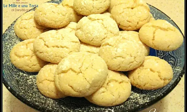 Un piatto di biscotti con farina di mandorle, spolverati di zucchero a velo, invitano a un momento di dolcezza.