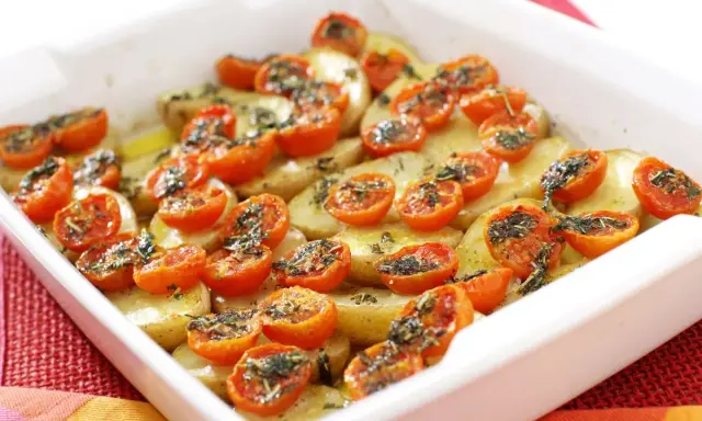 Parmigiana di patate al forno con pomodorini e erbe aromatiche, un piatto semplice e gustoso.