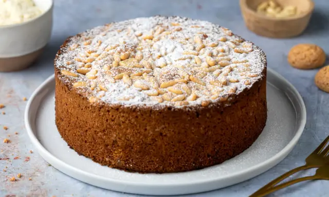 Torta soffice con farina di mandorle, guarnita con pinoli e zucchero a velo. Perfetta per ogni occasione.
