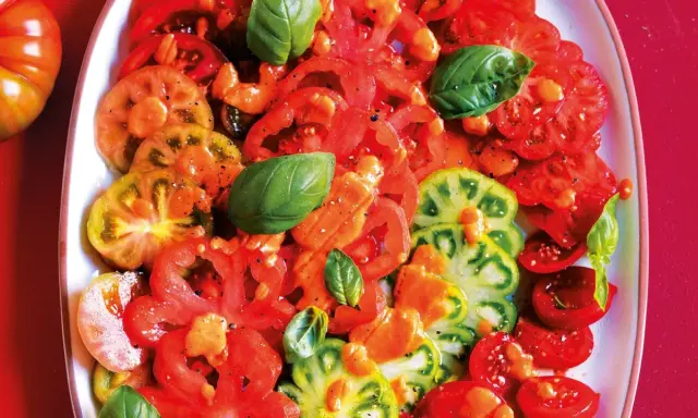 Un'insalata di pomodori colorati, affettati e conditi con erbe aromatiche fresche.