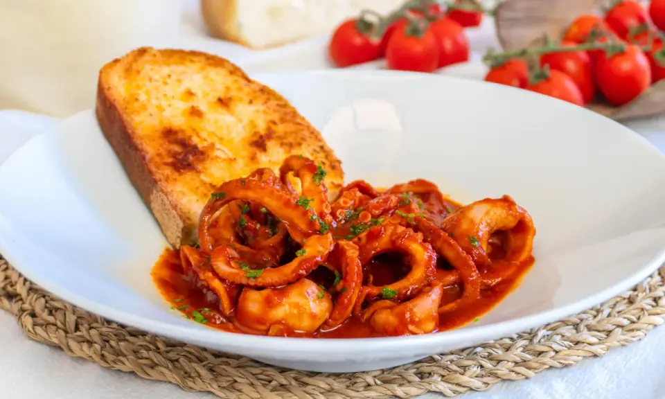 Moscardini in umido succulenti, serviti con pane tostato e pomodorini freschi. Un piatto che sa di mare e tradizione.