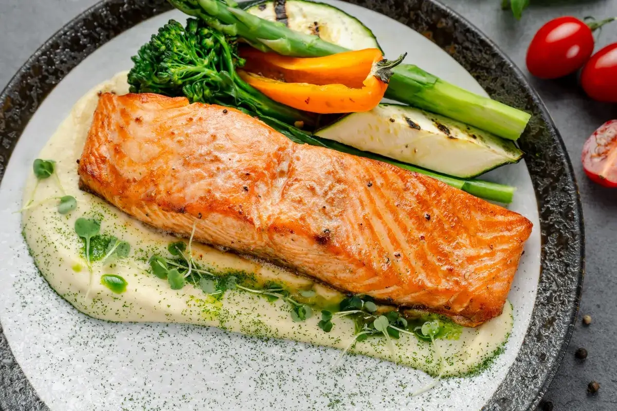 Succulento salmone in friggitrice ad aria su purè cremoso, con verdure grigliate e germogli freschi. Un piatto sano e gustoso.
