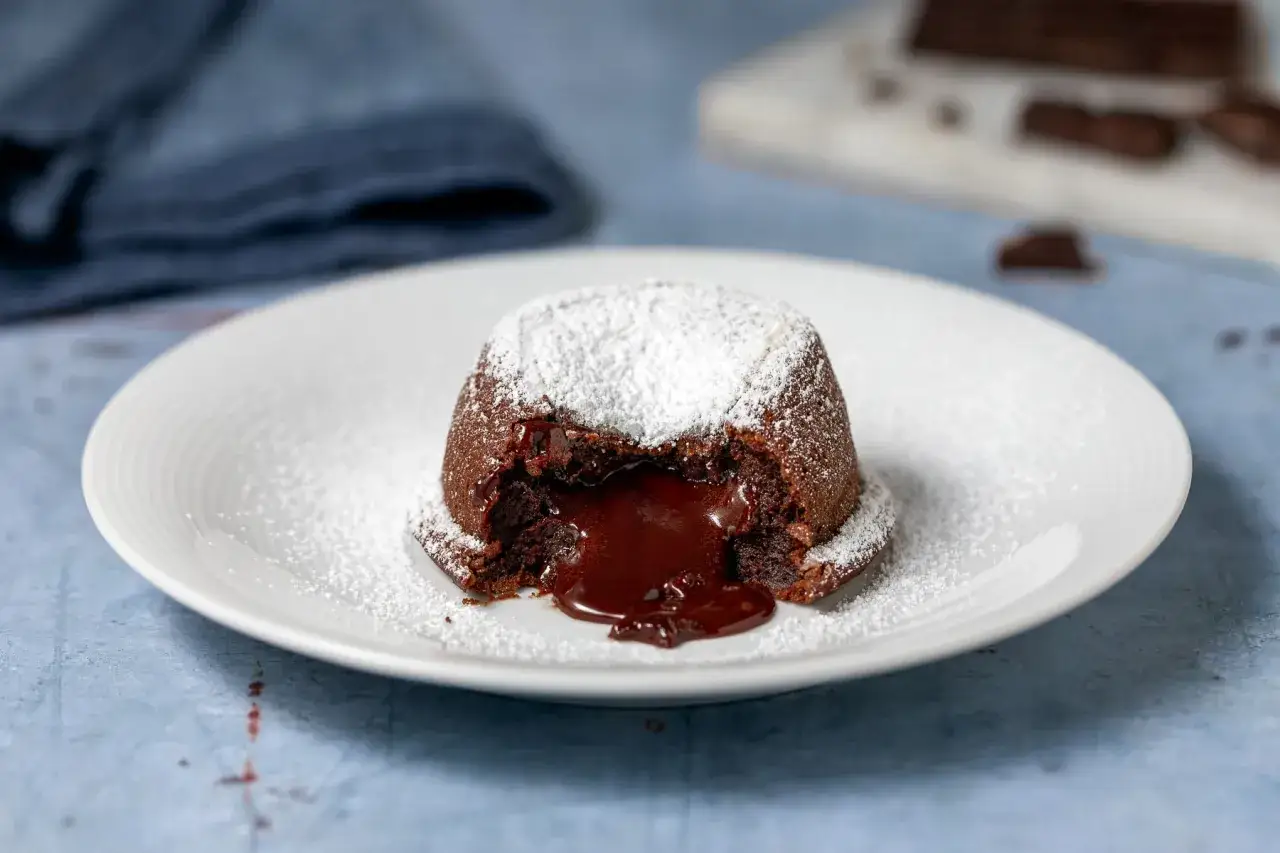Un tortino al cioccolato con cuore fondente, spolverato di zucchero a velo. Perfetto per dolci morbidi e veloci da gustare subito.